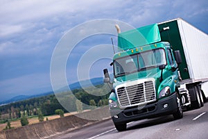 Green semi truck with container trailer on highway