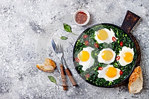 Green shakshuka with spinach, kale and peas. Healthy delicious breakfast. Top view, overhead, flat lay.