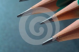 Green sharpened wooden pencils with black lead on a dark textured background. close-up