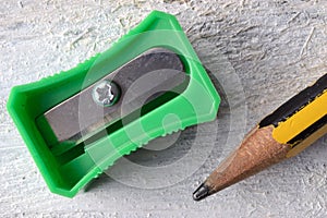 A green sharpener and a pencil on a white table.