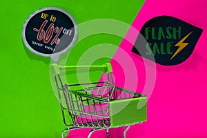 Green shopping cart. attached Up To -60% Off, Shop Now and Flash Sale text on green and pink background