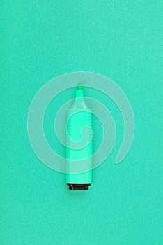 A green short wide marker without a cap is located vertically on the green cardboard