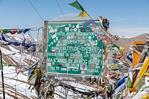 Green sign marking the summit of a high mountain pass in the Himalayas