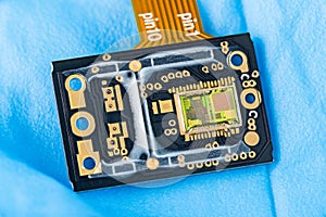 Green silicon die with photodiodes array on electronic PCB detail with orange flex cable