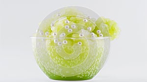 Green slushie topped with pearls in a frosted glass bowl on a white background