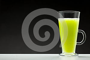 Green smoothie on black background with blank space for text