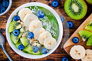 Green smoothie bowl with banana, kiwi, blueberry, granola and coconut