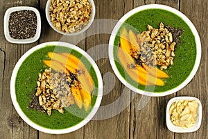 Green smoothie bowls with mangoes on wood background