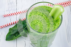 Green smoothie with celery, cucumber, spinach, apple and lemon on a white wooden background