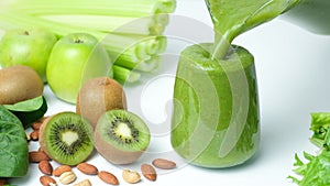 Green smoothie of celery, kiwi, green apple and spinach pouring into a glass, slow motion.