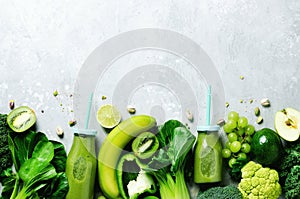 Green smoothie in glass jar with fresh organic green vegetables and fruits on grey background. Spring diet, healthy raw