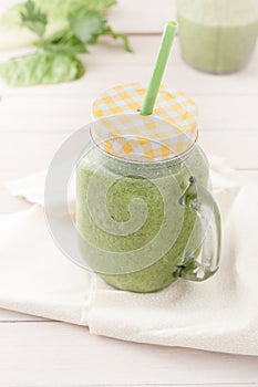 Green smoothie in a glass jar with lid and a straw