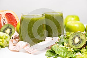 A green smoothie in a glass and a measuring tape. A healthy drink for weight loss