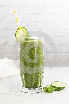 Green smoothie glass with spinach, banana blueberry, cucumber, avocado, bright kitchen background