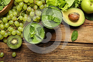 Green smoothie in glasses and fresh ingredients on wooden table, flat lay