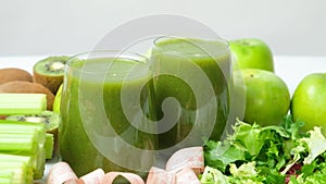 A green smoothie in glasses and a measuring tape. A healthy drink for weight loss