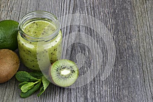 Green smoothie with kiwi fruit, cucumber, mint and parsley on old grey wooden desk