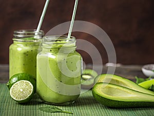 Green smoothie made by avocado, lemon and kiwi on natural green background