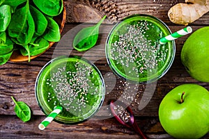Green smoothie with spinach, apple, ginger and chia seeds on a wooden background. top view