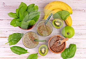 Green smoothie with spinach, banana, kiwi and green apple on a white wooden background. Flat lay.