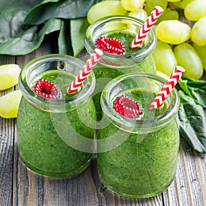 Green smoothie with spinach, grape and banana, garnished with raspberries, square