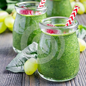 Green smoothie with spinach, grape and banana, garnished with raspberries, square