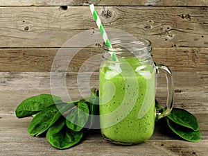 Sano frullato verde con spinaci in un vaso, tazza contro un legno sfondo.