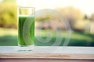 Green smoothie with spirulina on wood background