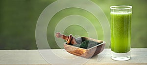 Green smoothie with spirulina on wood background