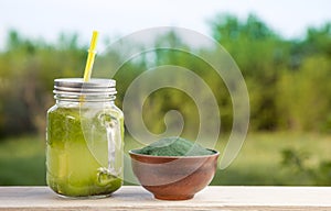 Green smoothie with spirulina on wood background