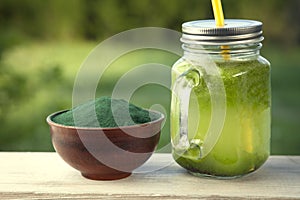 Green smoothie with spirulina on wood background