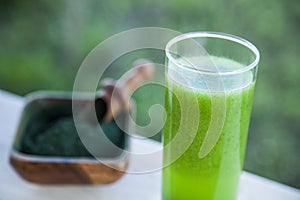 Green smoothie with spirulina on wood background