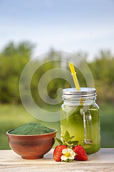 Green smoothie with spirulina on wood background