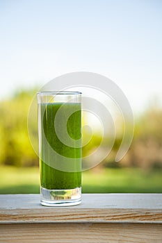 Green smoothie with spirulina on wood background