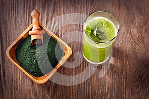 Green smoothie with spirulina on wood background