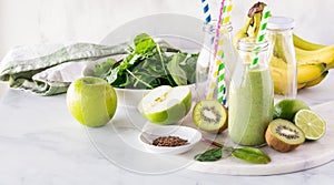 A green smoothie surrounded by ingredients used to make it.