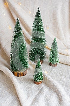 Green snowy Christmas trees decoration and lights on white textile background