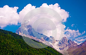 Green and snowy mountains, clouds and glacier in Georgia. Mountain landscape on sunny summer day