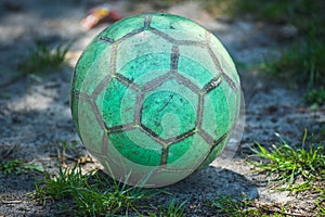 Green soccer ball lies on the ground.