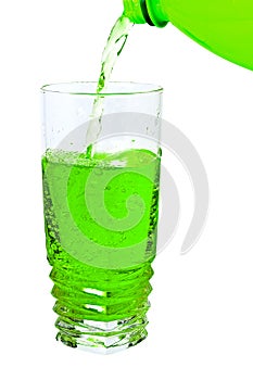 Green soda in a tall glass, pour from the bottle