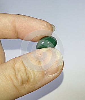 A green softgel in hand