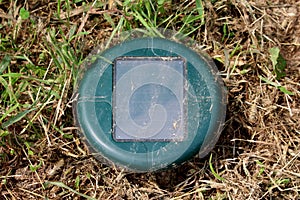 Green solar powered mole repeller used in local urban garden to repel moles and snakes surrounded with dry grass