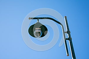 Green solar-powered street lamp. Solar-powered street lamp against the blue sky.