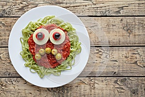 Green spaghetti pasta creative spooky halloween food monster with sad smile