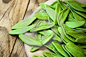 Green spinach italian pasta in the shape of olive leaves, scattered on wooden plate, mediterranean cuisine