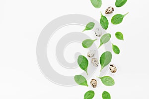 Green spinach leaves and quail eggs for a healthy breakfast on white background top view. Flat lay.