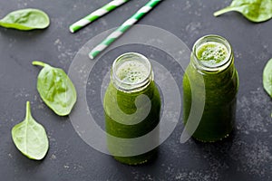 Green spinach smoothie in glass jar on dark black table, detox food for breakfast