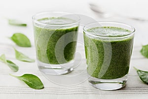 Green spinach smoothie in glass on white table