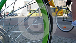 Green spoke wheel of a bicycle with traffic in the background, selected focus