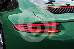 Green sports car with red backlight on. Closeup.